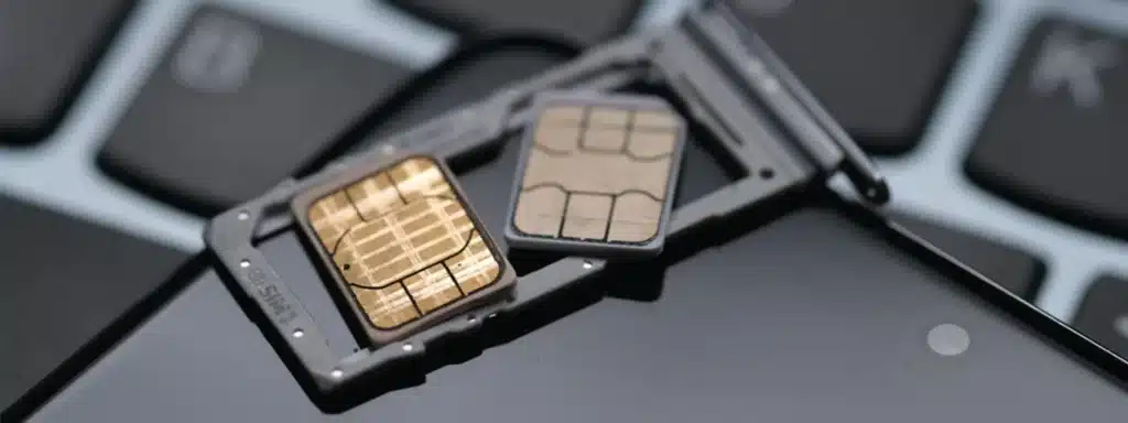Physical SIM card and nano-SIM on laptop keyboard – traditional alternative to multi-network SIM