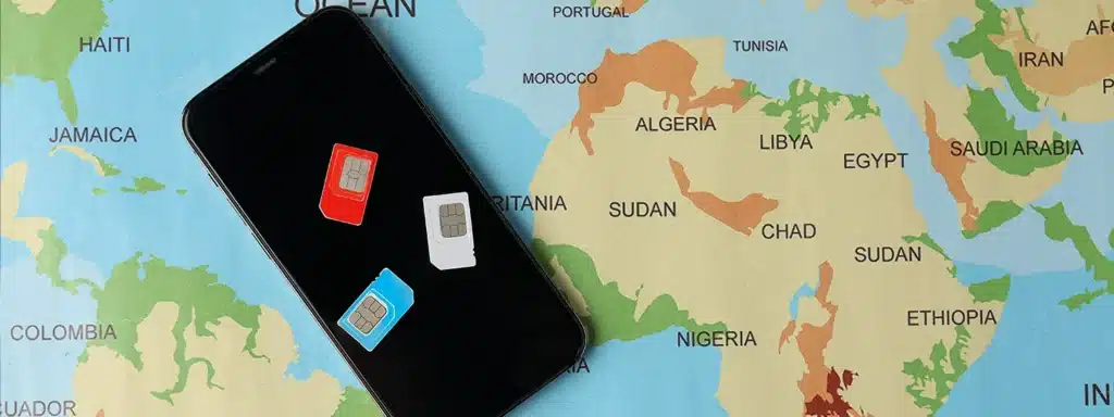 Multiple physical SIM cards on smartphone over world map – replaced by one multi-network SIM for global roaming