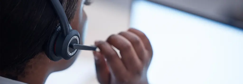 Woman speaks into headset to communicate with customer via VOiP
